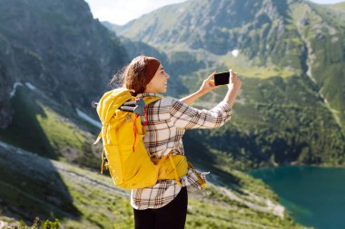 Olumlu turist kadın dışarıda fotoğraf çekiyor, vadi dağları manzaralı selfie çekiyor, seyahat maceralarını paylaşıyor. Yaşam tarzı, seyahat, turizm, aktif yaşam.