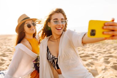 Yaz tatilinde sahilde selfie çeken şık güzel kadınlar. Arkadaşlar birlikte. ravel, blog yazma, hafta sonu, rahatlama ve yaşam tarzı konsepti.