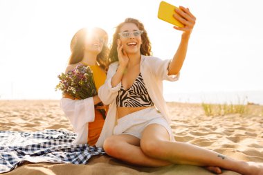 Yaz tatilinde sahilde selfie çeken şık güzel kadınlar. Arkadaşlar birlikte. ravel, blog yazma, hafta sonu, rahatlama ve yaşam tarzı konsepti.
