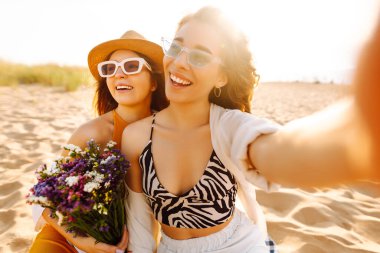 Yaz tatilinde sahilde selfie çeken şık güzel kadınlar. Arkadaşlar birlikte. ravel, blog yazma, hafta sonu, rahatlama ve yaşam tarzı konsepti.