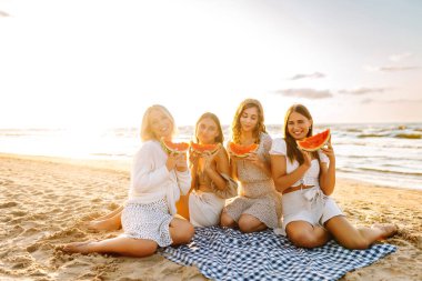 Plajda tatilde olan bayan arkadaşlar. Lezzetli yaz meyveleri yiyen kadınlar. Mutlu yaz zamanları. İnsanlar, yaşam tarzı, seyahat, doğa ve tatil kavramı.