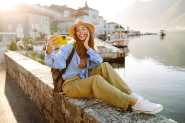 Güzel genç kız güneşli havanın tadını çıkarıyor. Sosyal ağdaki haberi için akıllı telefondan selfie çeken bir kadın. Yaşam tarzı olarak seyahat etmek.