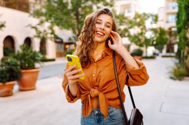 Akıllı telefon kullanan mutlu bir kadın, mesajlar atan bir cep telefonu, şehirle iletişim kuran. İş, teknoloji, blog, iletişim kavramı