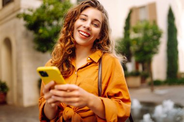 Akıllı telefon kullanan mutlu bir kadın, mesajlar atan bir cep telefonu, şehirle iletişim kuran. İş, teknoloji, blog, iletişim kavramı