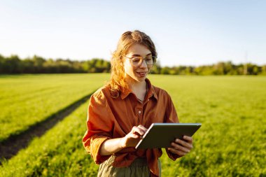 İnternet üzerinden tarım yönetimi. Yeşil tarlada tabletli bir kadın çiftçi. Çiftçilik ve sulama kavramı.