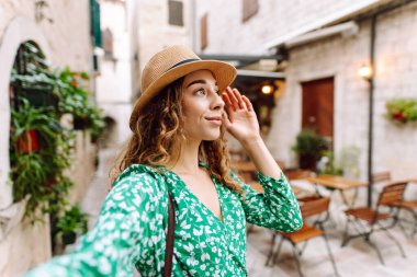 Güzel bir kadın sokakta yürüyor ve akıllı telefon kamerasıyla selfie çekiyor. Blogculuk, teknoloji, yaşam tarzı, seyahat, turizm, aktif yaşam.