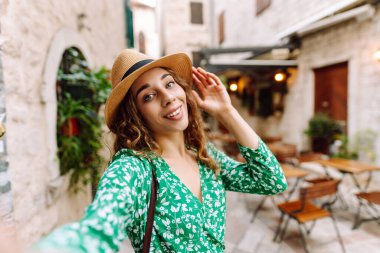 Güzel bir kadın sokakta yürüyor ve akıllı telefon kamerasıyla selfie çekiyor. Blogculuk, teknoloji, yaşam tarzı, seyahat, turizm, aktif yaşam.