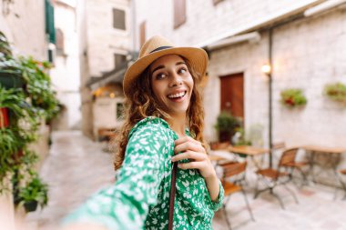 Güzel bir kadın sokakta yürüyor ve akıllı telefon kamerasıyla selfie çekiyor. Blogculuk, teknoloji, yaşam tarzı, seyahat, turizm, aktif yaşam.