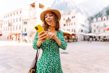 Güzel kadın sokaklarda cep telefonuyla dolaşıyor. Gezici uygulama kullanan bir turist. Seyahat, blog, hafta sonu, rahatlama ve yaşam tarzı konsepti.