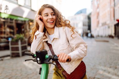 Mutlu kadın hafta sonu boş vakitlerinde elektrikli scooter kullanıyor. Ekolojik nakliye. Etkin yaşam biçimi.