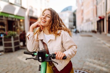 Mutlu kadın hafta sonu boş vakitlerinde elektrikli scooter kullanıyor. Ekolojik nakliye. Etkin yaşam biçimi.