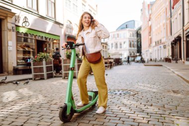 Mutlu kadın hafta sonu boş vakitlerinde elektrikli scooter kullanıyor. Ekolojik nakliye. Etkin yaşam biçimi.