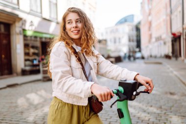 Mutlu kadın hafta sonu boş vakitlerinde elektrikli scooter kullanıyor. Ekolojik nakliye. Etkin yaşam biçimi.