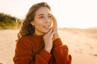 Gün batımında, soğuk havada güzel bir kumsalda yürüyen güzel bir kadının portresi. Seyahat, hafta sonu. Rahatlama, keyif, yalnızlık kavramı.