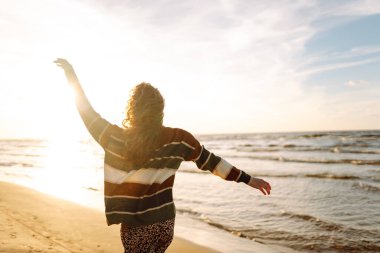 Gün batımında, soğuk havada güzel bir kumsalda yürüyen güzel bir kadının portresi. Seyahat, hafta sonu. Rahatlama, keyif, yalnızlık kavramı.