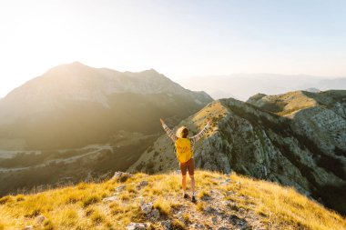 Dağ yamacında gezgin kadın gezgin. Manzaranın tadını çıkarıyor. Sırt çantasıyla dağlarda yürüyüş. Macera aktif.