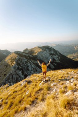 Dağ yamacında gezgin kadın gezgin. Manzaranın tadını çıkarıyor. Sırt çantasıyla dağlarda yürüyüş. Macera aktif.