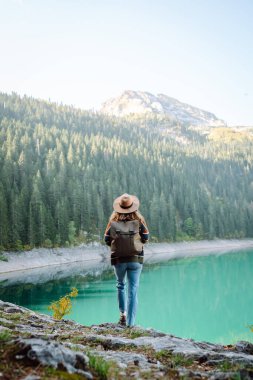 Genç bir kadın gezgin temiz havanın ve güzel bir göl ve dağ manzarasının tadını çıkarıyor. Aktif yaşam tarzı. Doğa, turizm konsepti.