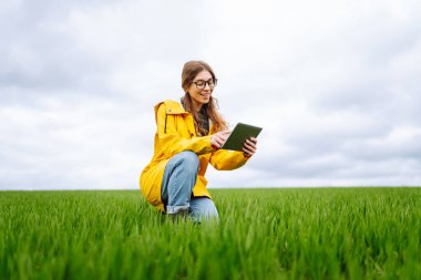 Kadın çiftçi yeşil alanda dijital tablette çalışıyor. Veri ve araştırma toplayın. Modern teknoloji.