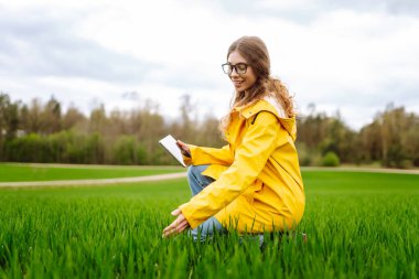 Kadın çiftçi yeşil alanda dijital tablette çalışıyor. Veri ve araştırma toplayın. Modern teknoloji.