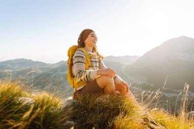 Genç ve güzel turist kadın tepenin üstünde dururken güzel doğanın tadını çıkarıyor. Doğa, seyahat, spor, aktif yaşam tarzı.