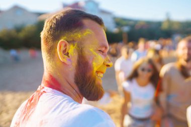 Holi festivali. Giysileri ve vücutları renkli boyalı gençler birlikte eğleniyor. Plaj partisi. Arkadaşlık, dinlenme, tatil.