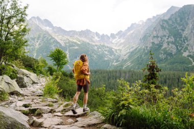 Sırt çantalı aktif kadın turist görkemli dağların güzel manzarasının tadını çıkarıyor. Seyahat, macera. Etkin bir yaşam biçimi kavramı.