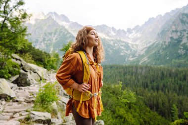 Sırt çantalı aktif kadın turist görkemli dağların güzel manzarasının tadını çıkarıyor. Seyahat, macera. Etkin bir yaşam biçimi kavramı.