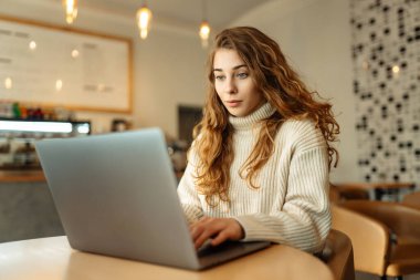 Rahat bir kafede otururken bilgisayarını kullanan serbest çalışan bir kadın. Eğitim ve iş kavramı. İnternetten alışveriş.