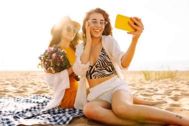 Tropik deniz kıyısında selfie çeken iki mutlu kadın. Arkadaşlar birlikte. Seyahat, blog, hafta sonu, rahatlama ve yaşam tarzı konsepti.