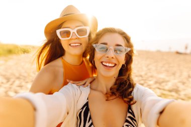 Tropik deniz kıyısında selfie çeken iki mutlu kadın. Arkadaşlar birlikte. Seyahat, blog, hafta sonu, rahatlama ve yaşam tarzı konsepti.