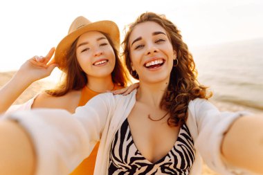Tropik deniz kıyısında selfie çeken iki mutlu kadın. Arkadaşlar birlikte. Seyahat, blog, hafta sonu, rahatlama ve yaşam tarzı konsepti.