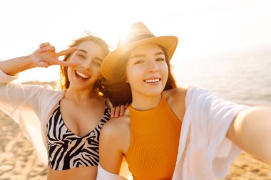 Tropik deniz kıyısında selfie çeken iki mutlu kadın. Arkadaşlar birlikte. Seyahat, blog, hafta sonu, rahatlama ve yaşam tarzı konsepti.