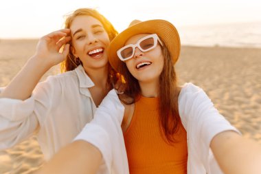 Tropik deniz kıyısında selfie çeken iki mutlu kadın. Arkadaşlar birlikte. Seyahat, blog, hafta sonu, rahatlama ve yaşam tarzı konsepti.