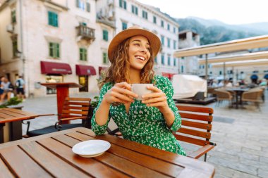 Mutlu kadın yaz güneşli bir günde, açık hava kaldırım kafe restoranının kahvesini yudumluyor. İnsanlar, moda, yaşam tarzı, seyahat ve tatiller