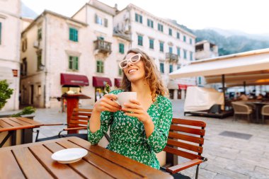 Mutlu kadın yaz güneşli bir günde, açık hava kaldırım kafe restoranının kahvesini yudumluyor. İnsanlar, moda, yaşam tarzı, seyahat ve tatiller