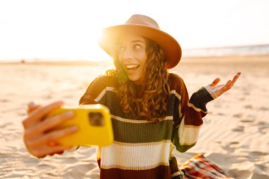 Sahilde yaşayan akıllı telefon özçekimi kullanan genç bir kadının portresi. Teknoloji ve yaşam tarzı seyahat ve seyahat kavramı