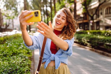 Güzel bir kadın cep telefonuyla sokaklarda dolaşıyor ve selfie çekiyor. Seyahat, blog, hafta sonu, rahatlama ve yaşam tarzı konsepti.