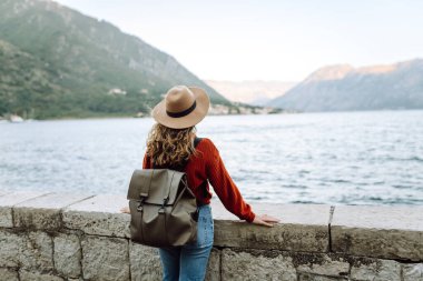 Arkaya bakan genç bayan turist şehrin rengarenk manzarasına ve dağ koyunun manzarasına hayran. Yaşam tarzı, tatil, dinlenme, aktif yaşam.