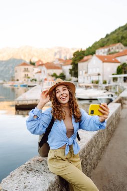 Şehrin ve körfezin arka planında selfie çeken genç bir kadın. Seyahat, turizm, teknoloji, blog, iletişim kavramı.