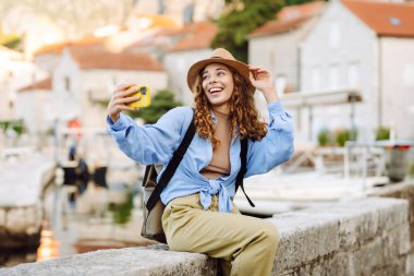 Şehrin ve körfezin arka planında selfie çeken genç bir kadın. Seyahat, turizm, teknoloji, blog, iletişim kavramı.