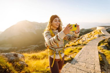 Negosh Anıtmezarı 'nın Popüler Turist Çekimi' ndeki genç kadın telefon için fotoğraf çekiyor. Turizm, doğa, blog konsepti.