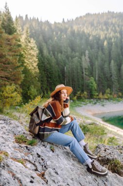 Dişi gezgin dağların arasındaki göl manzarasının tadını çıkarıyor. Çevre turizmi. Etkin yaşam biçimi.