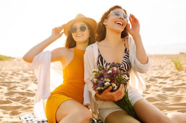 Kumsalda birlikte yürüyen iki genç kadın. Seyahat, hafta sonu, rahatlama ve yaşam tarzı konsepti.