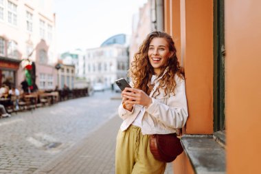 Telefonu olan mutlu bir kadın, yaz tatillerinde sokaklarda mesajlaşan bir kadın. Seyahat, blog, hafta sonu, rahatlama ve yaşam tarzı konsepti.