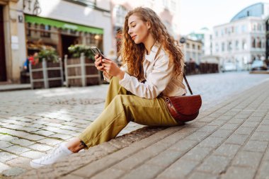 Telefonu olan mutlu bir kadın, yaz tatillerinde sokaklarda mesajlaşan bir kadın. Seyahat, blog, hafta sonu, rahatlama ve yaşam tarzı konsepti.