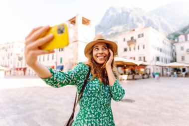 Mutlu kadın, eski şehrin arka planında akıllı telefondan fotoğraf çekiyor. İtalya 'da seyahat ve yaşam.