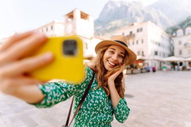 Mutlu kadın, eski şehrin arka planında akıllı telefondan fotoğraf çekiyor. İtalya 'da seyahat ve yaşam.