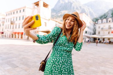 Mutlu kadın, eski şehrin arka planında akıllı telefondan fotoğraf çekiyor. İtalya 'da seyahat ve yaşam.