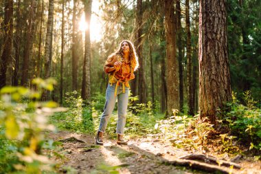 Kadın turist sarı sırt çantasıyla bahar ormanlarında yürüyüş yapıyor. Doğada yürüyüş ve neşe. Dişi yürüyüşçü ormanı keşfediyor..